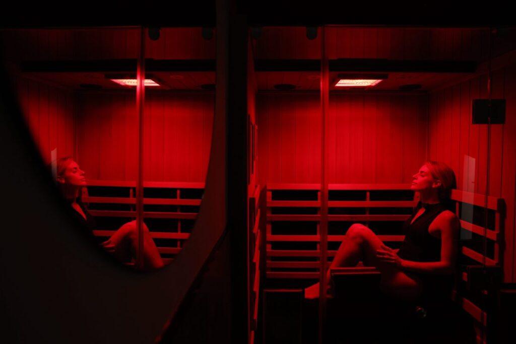 Guest relaxing in a red-lit private infrared sauna at Beit Sisu, Dubai Media City